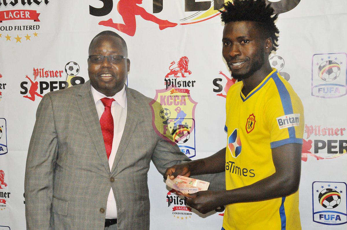 FUFA official Rogers Byamukama rewards man of the match Allan Kyambadde after the fixture